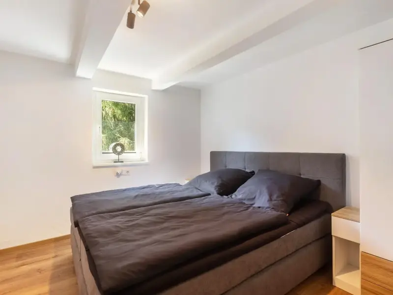 Schlafzimmer mit Boxspringbett und grossem Fenster, Ferienwohnung Bödefeld