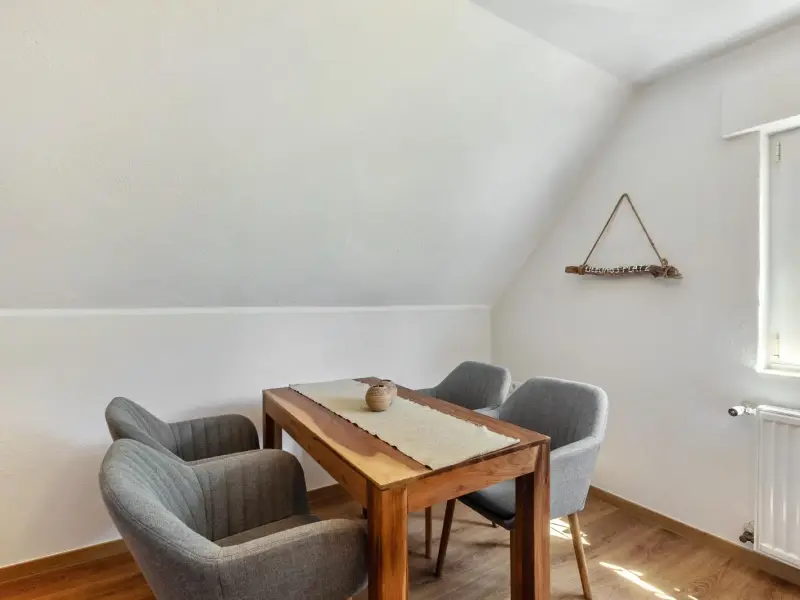 Essecke unter der Dachschräge mit Holztisch und gepolsterten Sesseln, Ferienwohnung Gellinghausen