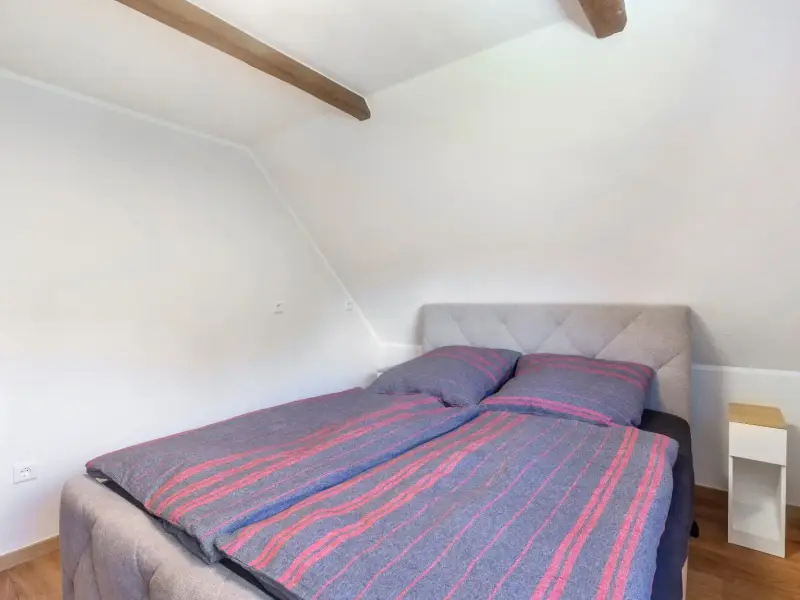 Schlafzimmer unter der Dachschräge mit sichtbarem Holzbalken, Ferienwohnung Gellinghausen